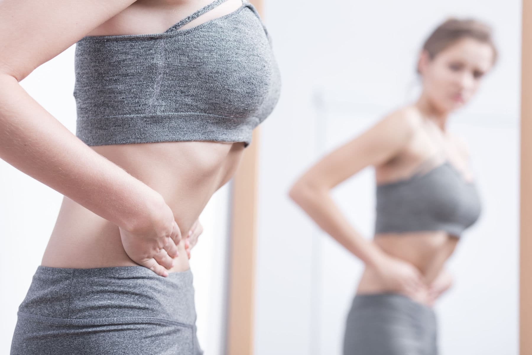Woman looking at her body in the mirror