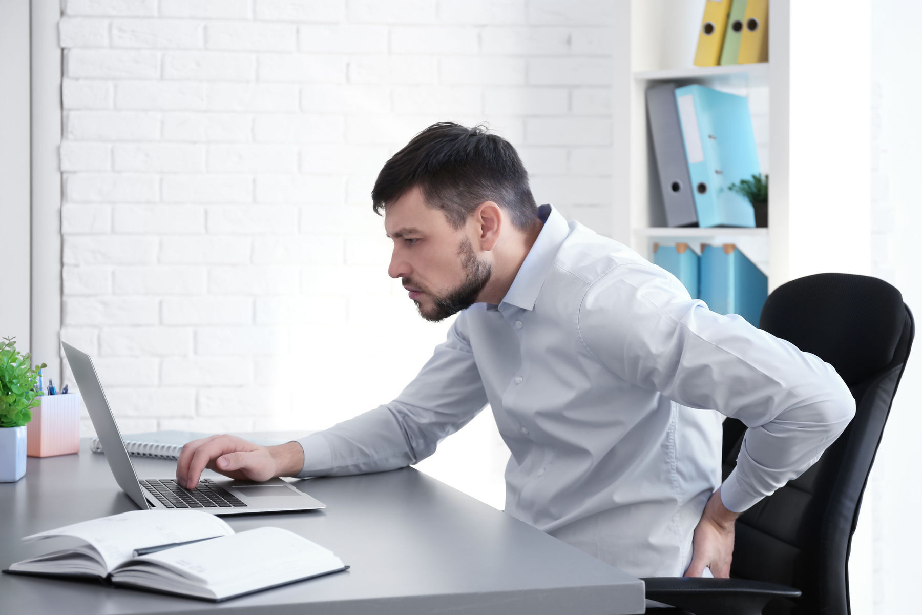 Man sitting with bad posture which will result in workplace injury