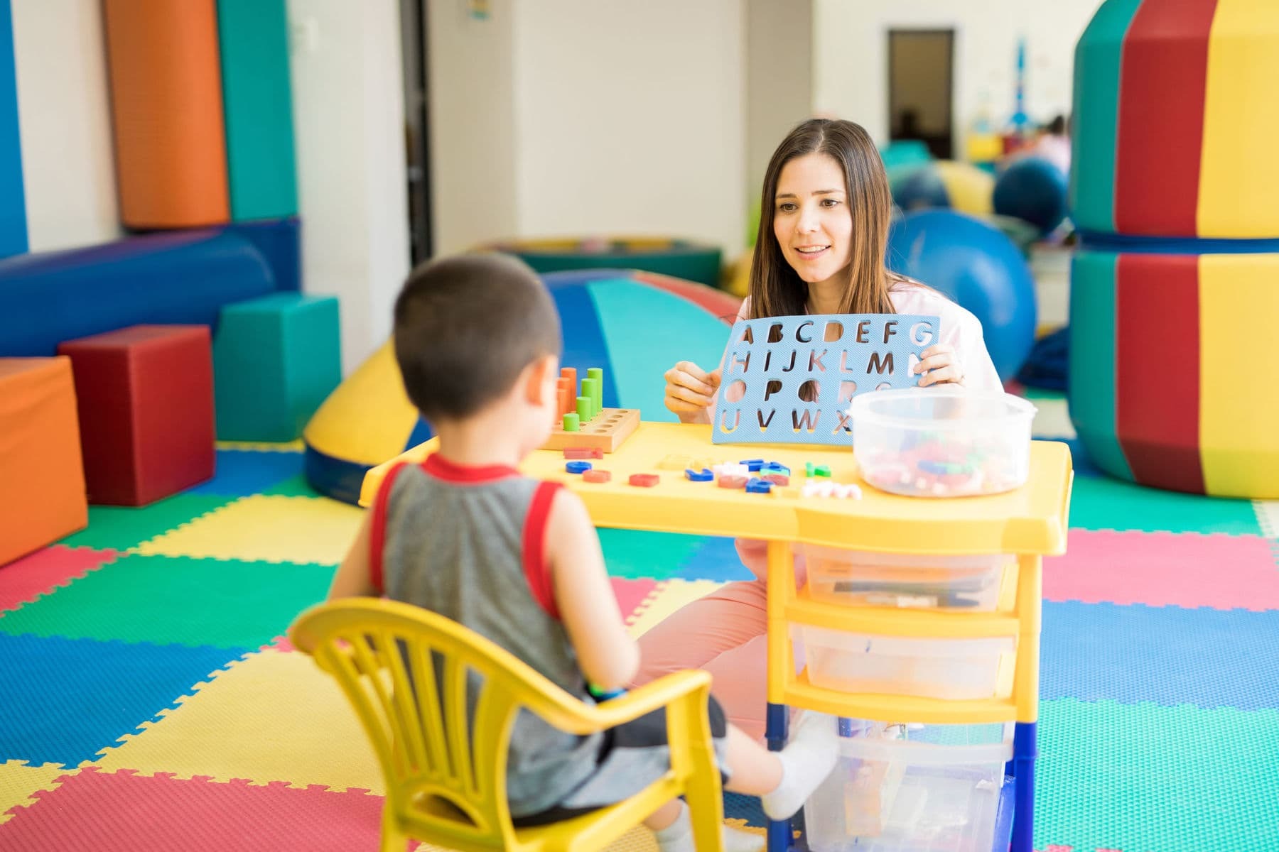 Therapist talking to young sad boy Child mental health therapist using play therapy to help young boy