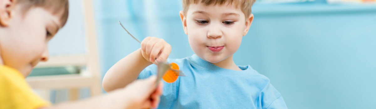 Young children eating their lunch in a nursery that complies with Ofsted food hygiene requirements