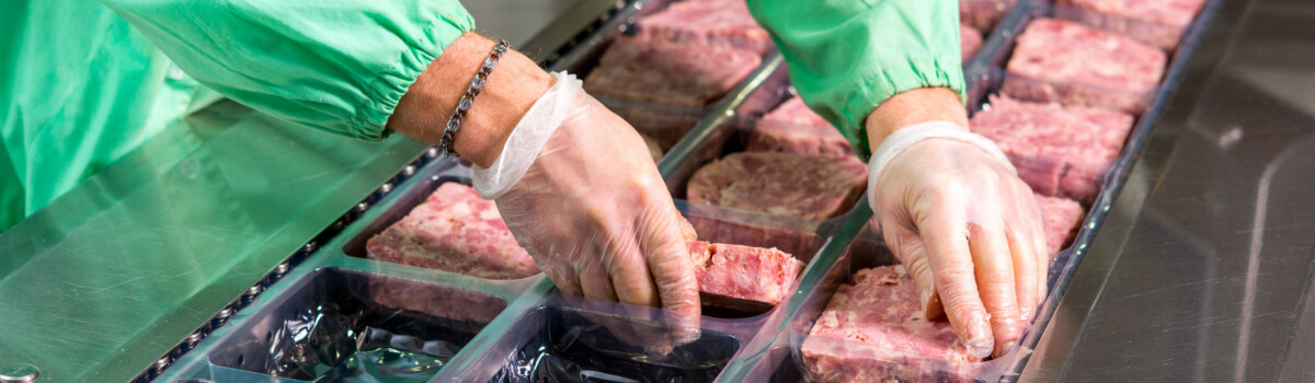 Worker processing raw meat to avoid any allergen contamination Manufacturers processing raw meat to avoid any allergen contamination