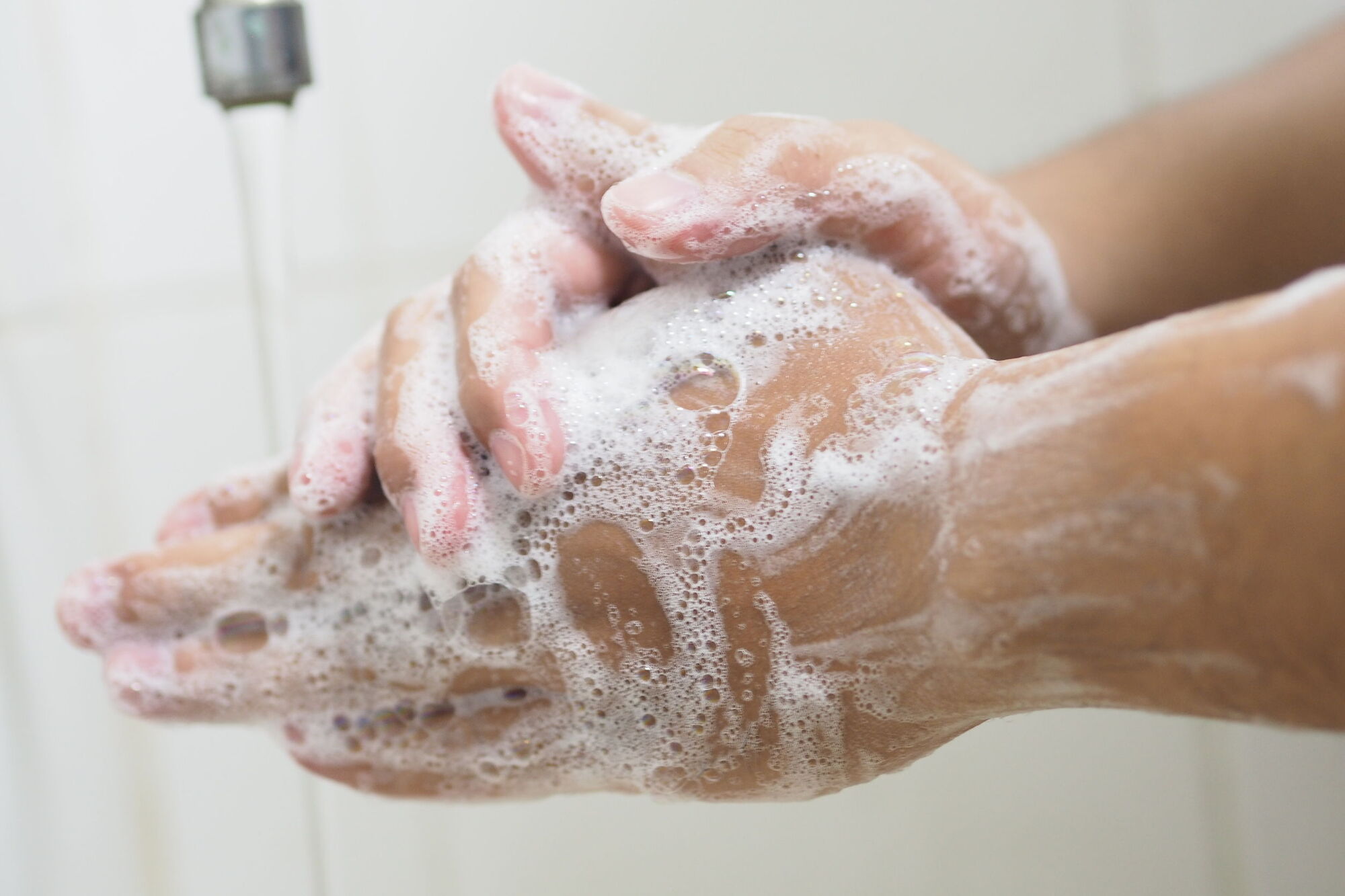 Woman washing her hands after touching raw meat to reduce the risk of cross contamination Woman washing her hands after touching raw meat to reduce the risk of cross contamination