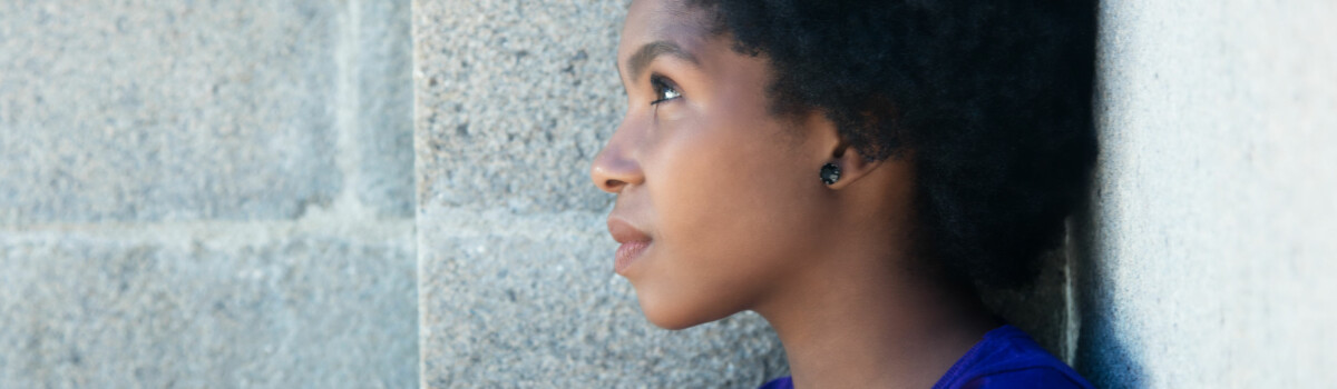 Young woman stood against the wall staring off into the distance, after a upsetting day dealing with Female Gential Mutilation cases