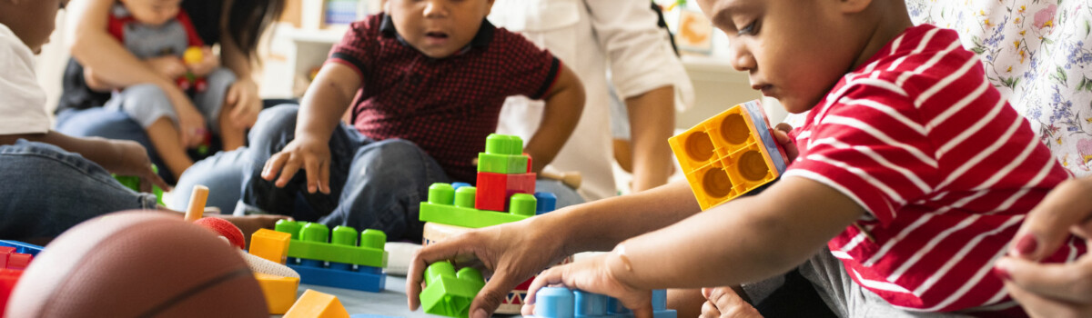 Nursery staff playing with children while manager sorts out RIDDOR report