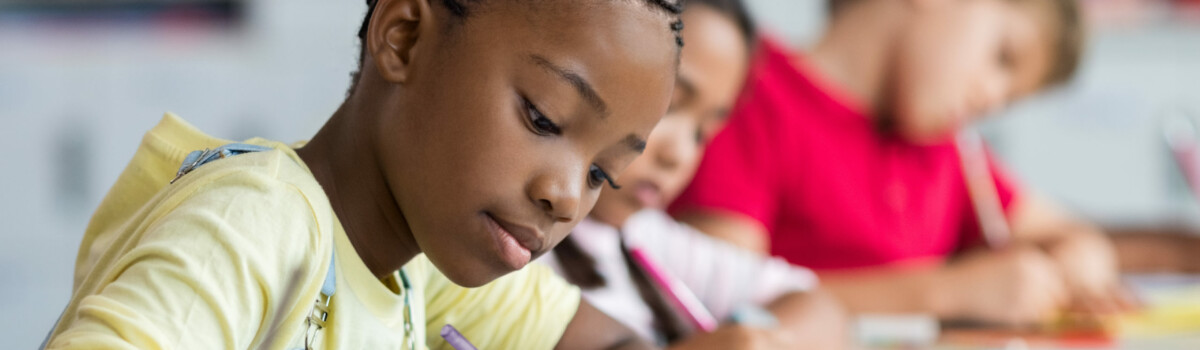 Child writing down her questions for debate on equality and diversity