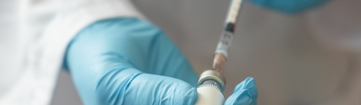 Doctor getting ready to give injection, ensuring he wears gloves to protect himself from fluids