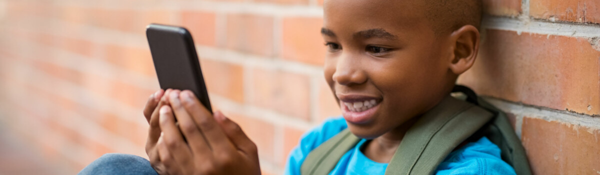 Child Playing On Phone As He Plays Online Safely