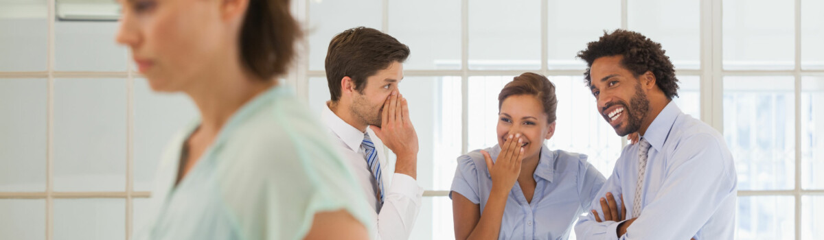 Colleagues gossiping about another worker in front of her