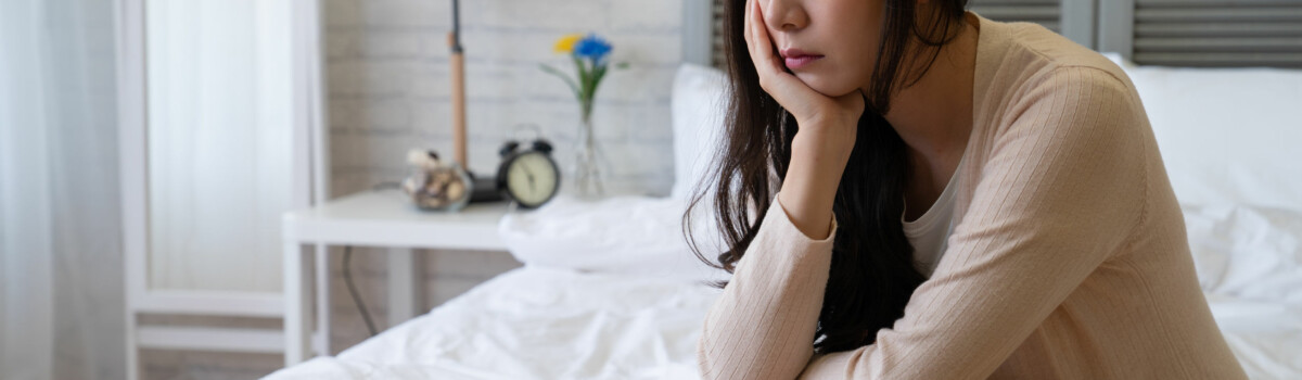 Parent sat on end of bed exhausted and struggling to juggle everything