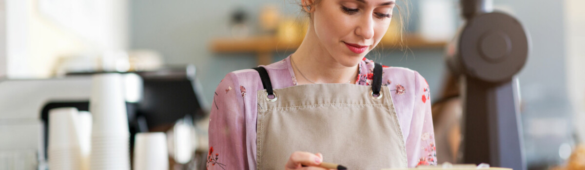 Cafe owner ensuring she follows good hygiene practices while handling food and drink