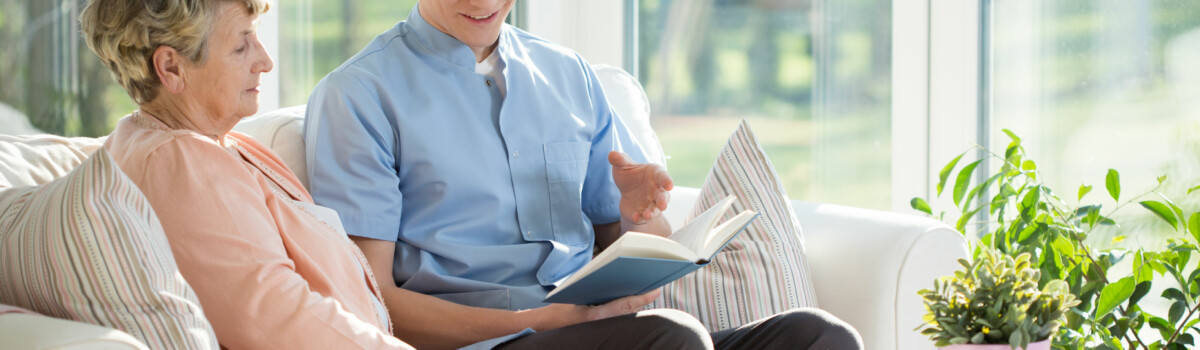 Carer reading to elderly patient