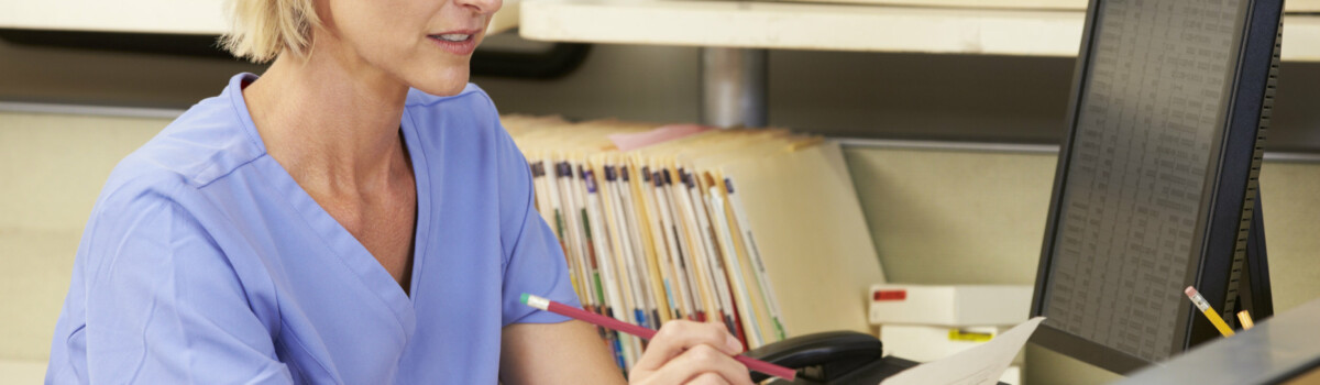 Nurse working in hospital sat at nursing station