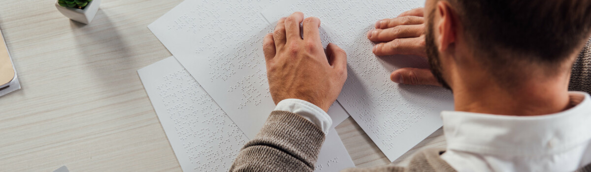 Man who is blind using braille to read at work