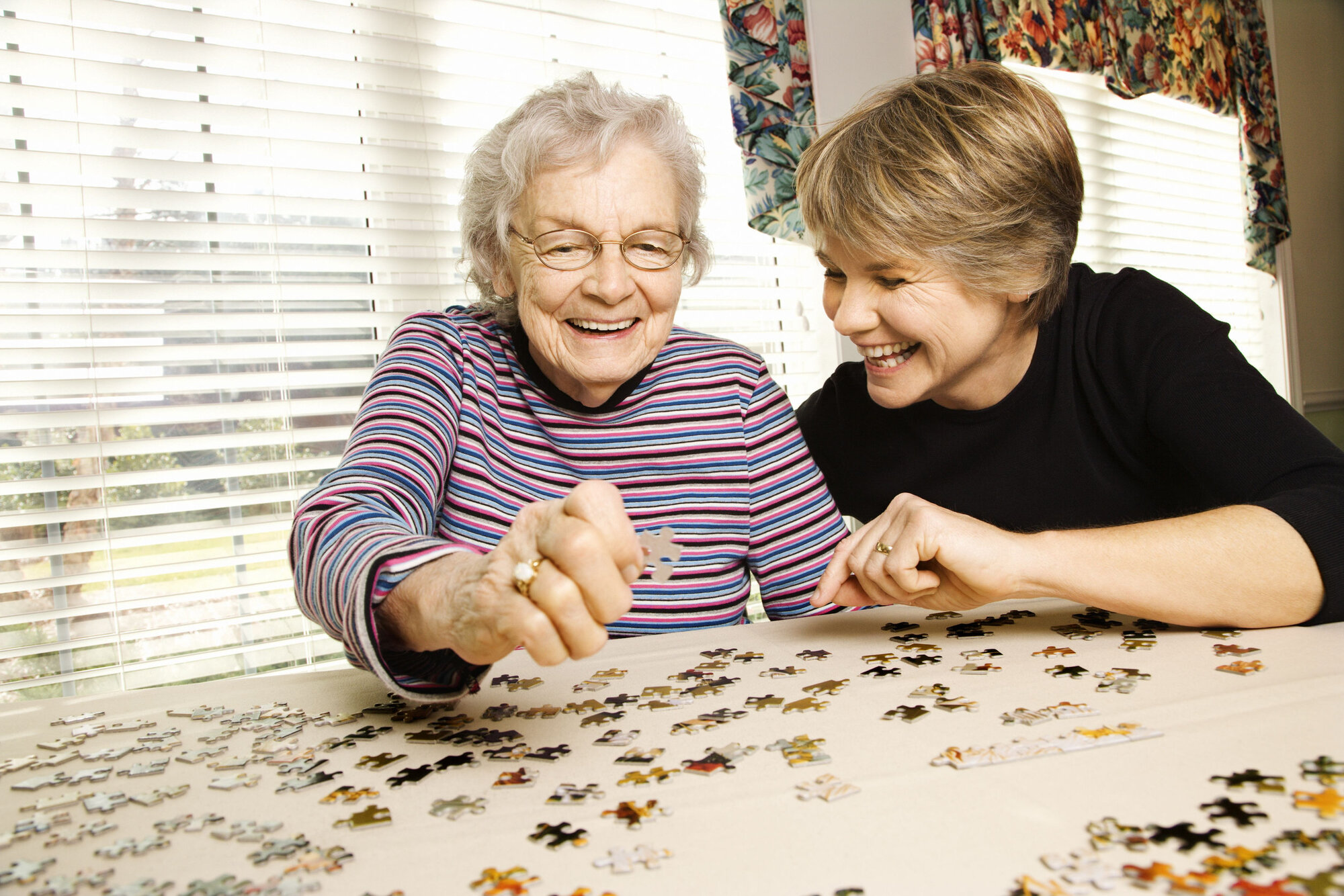 Elderly woman doing a jigsaw with her daughter Elderly woman doing a jigsaw with her daughter