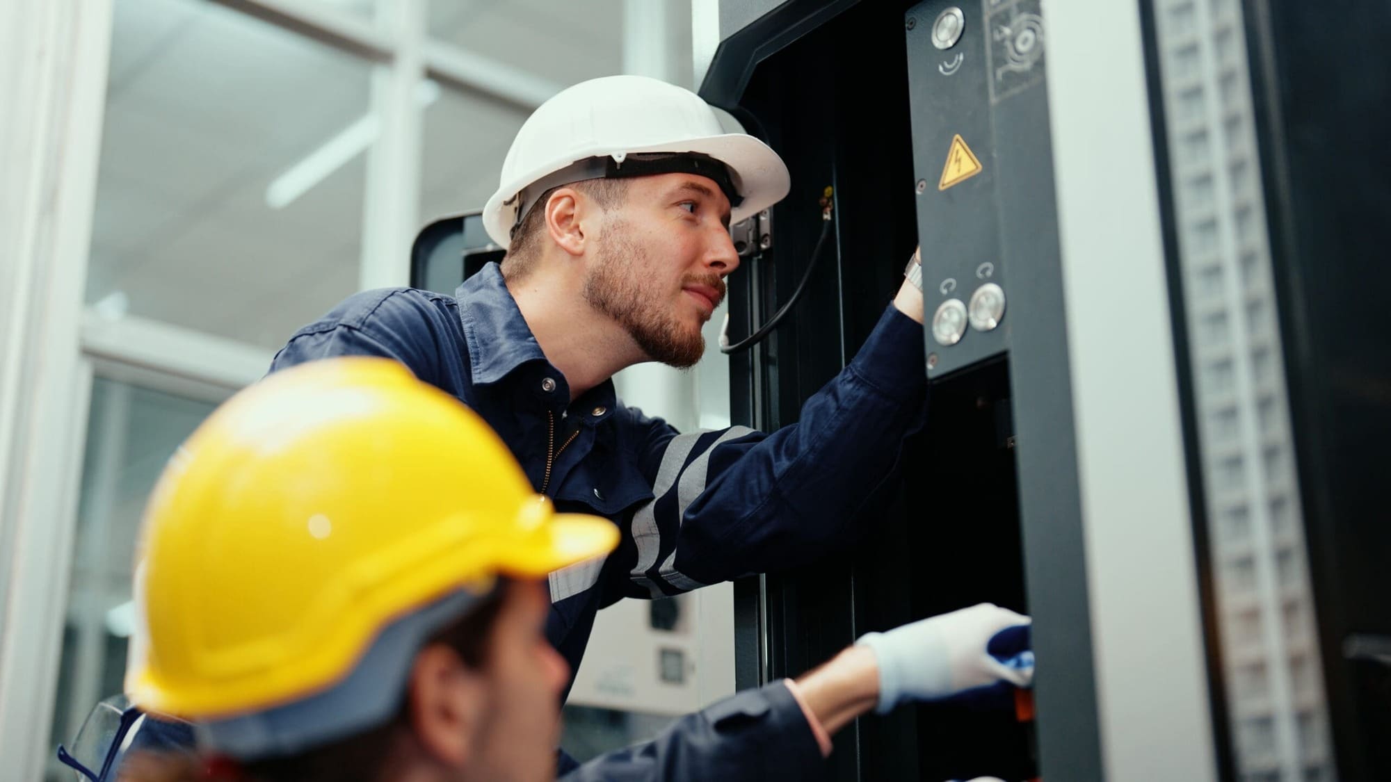Electrical Safety: The Role of Regular Inspections and Maintenance 4 electrical engineers in safety wear maintaining CNC machine